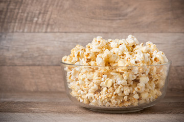 Popcorn in a bowl on the wooden table.