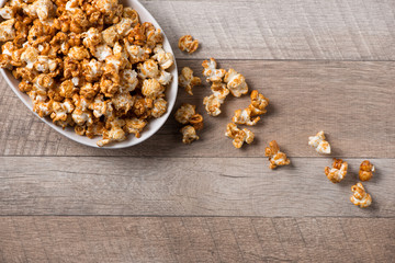 Caramel opcorn in bowl on the wooden table.