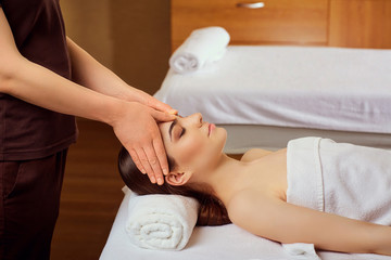 Obraz na płótnie Canvas Facial massage for a beautiful young woman at a spa salon.