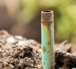 Rusty metal pipe in the ground for water