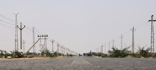 Fototapeta premium Hitzeflimmern auf der schnurgeraden Landstraße zwischen Bikaner und Jaisalmer, Rajasthan, Indien