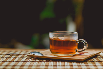 Glass cup of tea, teaspoon on wooden table.