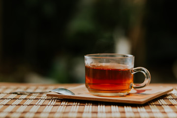 Glass cup of tea, teaspoon on wooden table.