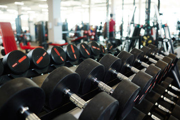 Fototapeta na wymiar Background image: row of dumbbells on rack in empty modern gym