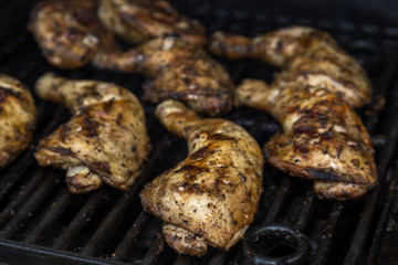 Chicken leg quarter thighs on a barbecue grill, golden and juicy -  front view