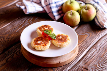 Cheese pancakes, syrniki with red currant on a white plate