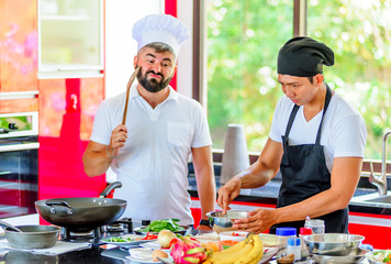 Colleagues at work: Thai and European chefs at the kitchen doing Thai food