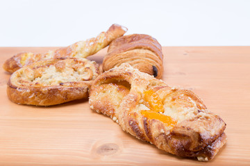 Sweet french pastries with fruits and cream on a natural oak wood table with white background