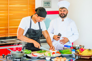 Colleagues at work: Thai and European chefs at the kitchen doing Thai food