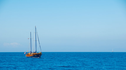 A ship with the sails down on the sea horizon.