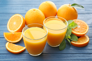 Glasses of fresh juice and fruit slices on wooden background