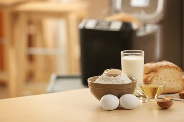 Fototapeta na wymiar Sliced loaf with ingredients and blurred bread machine on background