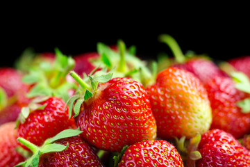 Harvest of fresh organic strawberries isolated on black background macro image