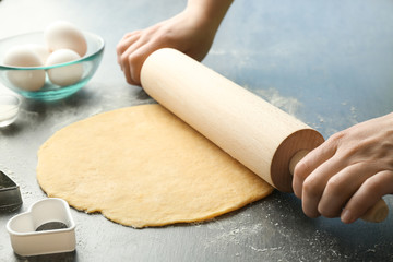 Woman rolling dough for butter cookies on table