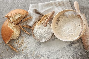 Fototapeta na wymiar Bowl with flour, sieve and bread chunk on light background