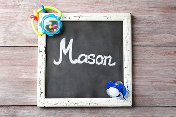 Chalkboard with name MASON on wooden background. Concept of choosing baby name