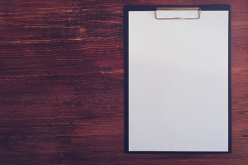 Empty clipboard on wooden table, top view