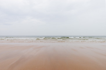 sandy beach and wavy sea surface on the wales coast on a cloudy day