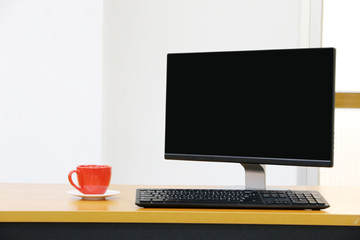 office workspace with screen computer, Red coffee cup at home or studio,Copy space