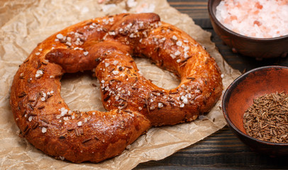 Pretzel with caraway seeds and coarse salt on a dark wooden table. Selective focus.  Top view