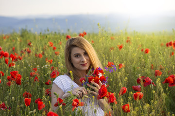 Woman in poppy field holding a bouquet of poppies