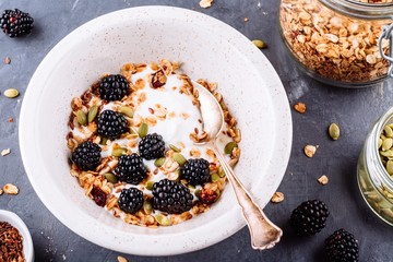 Healthy breakfast bowl of yogurt with granola, flax seeds,  pumpkin seeds and fresh blackberries