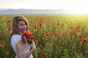 Woman in poppy field holding a bouquet of poppies