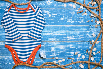 Baby Child summer stuff to the beach on a blue wooden background with rope and sea shells. Top view with copy space for text.