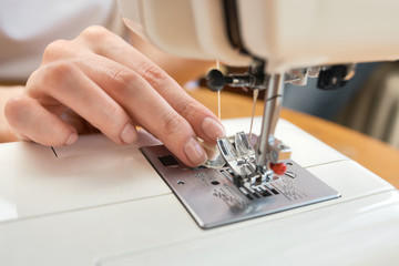 Female tailor threading bobbin into sewing machine case