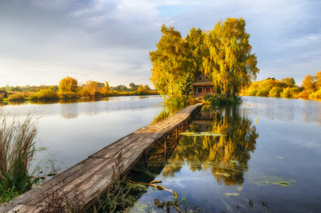 House on the island. Bridge on a river to a picturesque hut