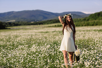 Fototapeta na wymiar Woman enjoying daisy field, nice female lying down in meadow of flowers, pretty girl relaxing outdoor, having fun, holding plant, happy young lady and spring green nature, harmony concept