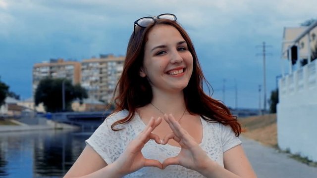 Ginger hair girl make Hand heart sign by her fingers