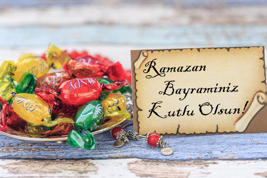 Happy eid al fitr in turkish on the card with candies on vintage table