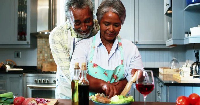 Senior African American couple preparing salad in kitchen