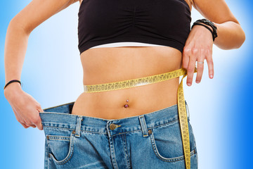 Young woman measuring her waistline after a diet