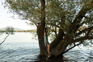 Giovane donna in abito elegante tra gli alberi sul lago