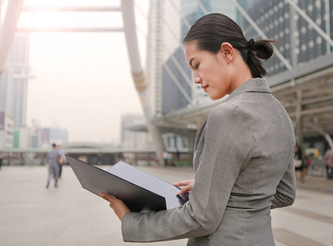 Beautiful business woman open cover sheet in her hands outdoors.