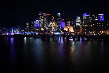 Beautiful scene of colorful Sydney city skyline by night at Campbell's Cove during Vivid Sydney Lights Festival. Free annual outdoor event of light music and ideas.
