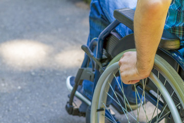 Hand of young man on the wheel of wheelchair