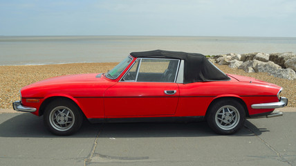 Classic Red Triumph Stag Motor Car Parked on Seafront Promenade.