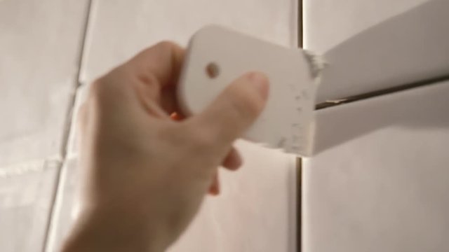 Worker putting tiles on the wall in the kitchen. His hands are placing the tile on the adhesive.