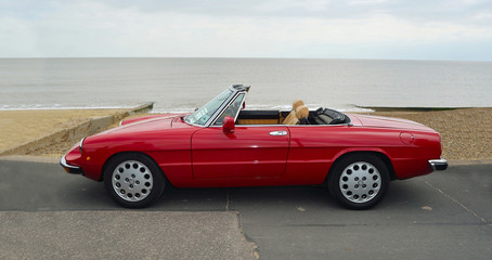 Classic Red Italian Sports  Convertible  Motor Car Parked on Seafront Promenade.