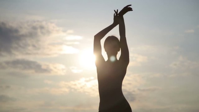 Young beautiful woman is dancing wearing body suit on sunrise in the desert. Creative authentic concept.