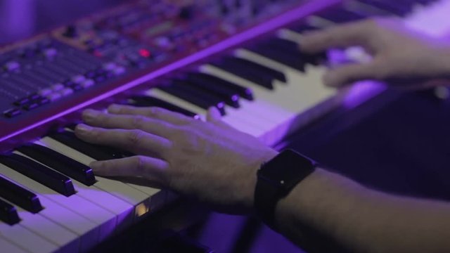 Musician playing on the keyboard synthesizer piano keys. Musician plays a musical instrument on the concert stage
