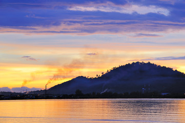 Beautiful sunrise over sea with factory pollution