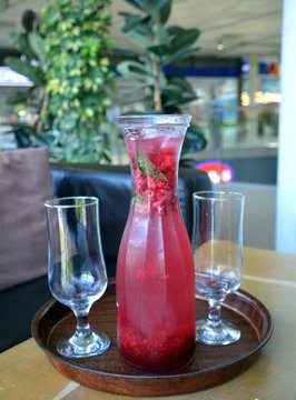 Summer lemonade with raspberry and leaves mint in a glass jug