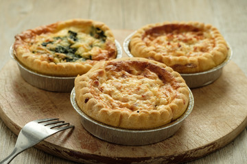 Mehrere Quiche Lorraine auf einem Brett mit Gabel