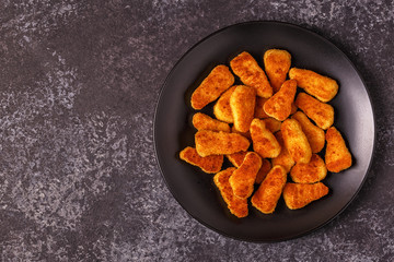 Chicken nuggets with sauces on dark background.