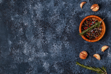 Dark food background with rosemary, garlic and pepper.