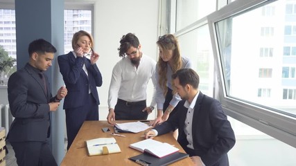 Director of the company holds a meeting with his subordinates. Managers view the documents in the office. Colleagues at office desk.